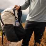 Super-ultralight backpacking kit beside a fitted women's pack on a forest trail